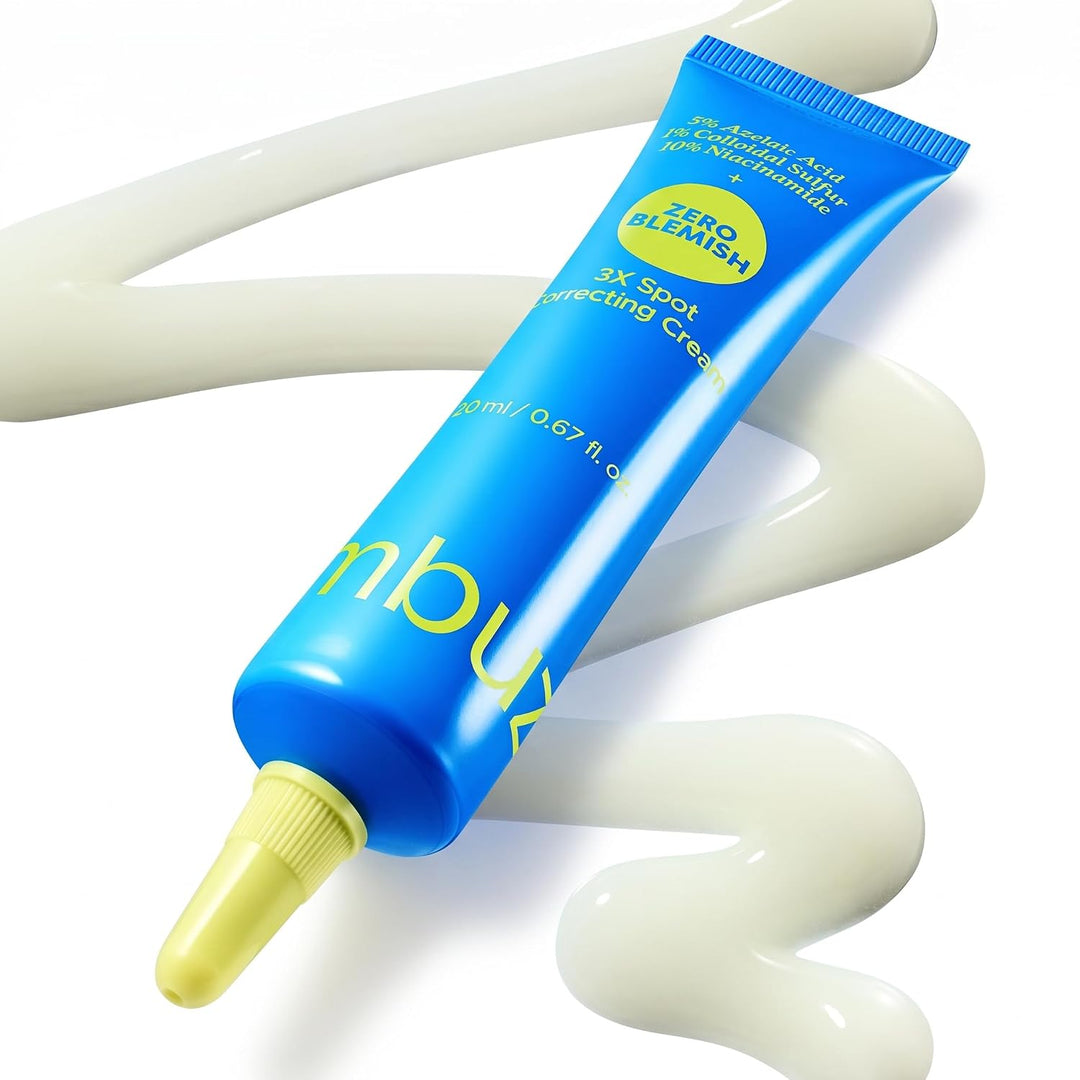 A blue squeeze tube of Blumish Zero Bligh 3X Spot Correcting Cream with a yellow applicator tip, shown diagonally on a white background with decorative cream swirls.